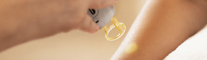 Is Laser Safe for Asian Skin? Debunking Myths and Highlighting Best Practices A person receiving a laser facial treatment with a handheld device emitting blue light, held by a gloved professional in a clinical setting.